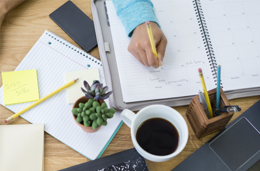 Desk with diary, mobile device, cup of coffee, pens & pencils on