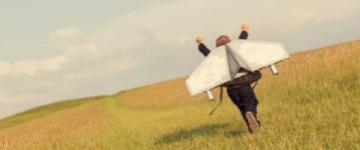 Boy running wearing aeroplane wings