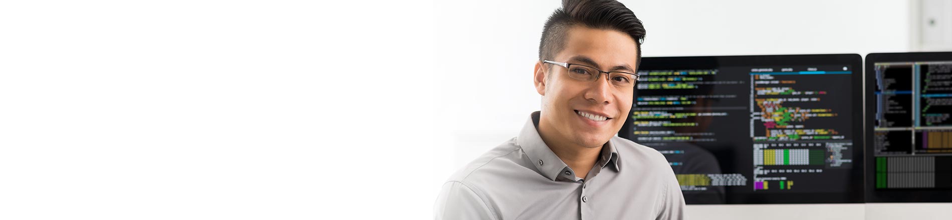 Man in glasses in front of computer screens